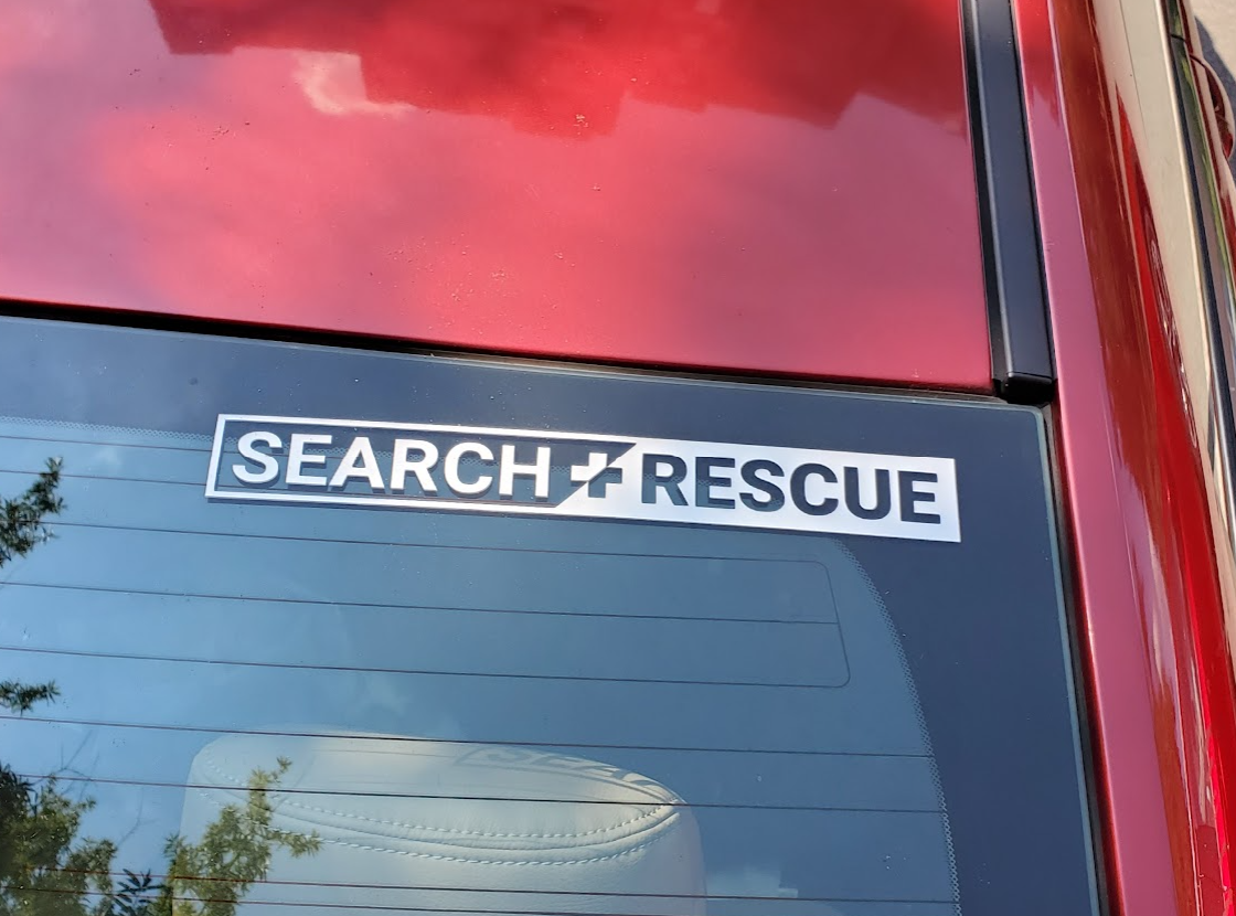 White SEARCH + RESCUE vinyl banner decal applied to a vehicle's rear window